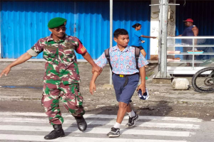 Peduli Keselamatan, Babinsa Timika Bantu Penyeberangan Anak Sekolah di Jalan Padat