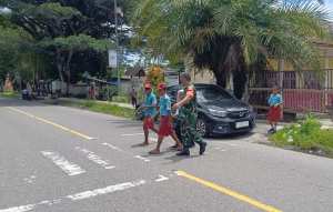 Babinsa Kodim 1710/Mimika Rutin Kawal Siswa Menyeberang Jalan